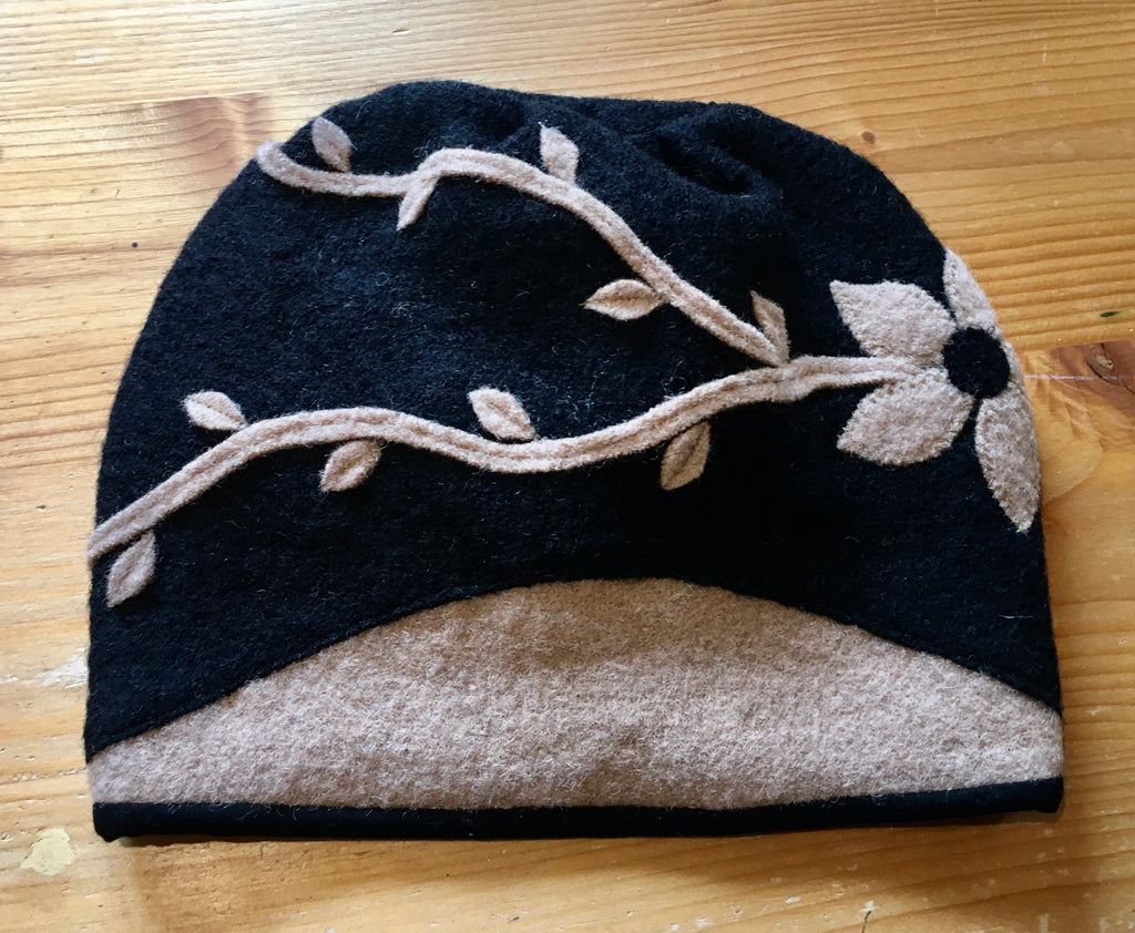 Haube „Leetah“ mit seitlicher Blume und Blätterranken in schwarz/camel/ gefüttert